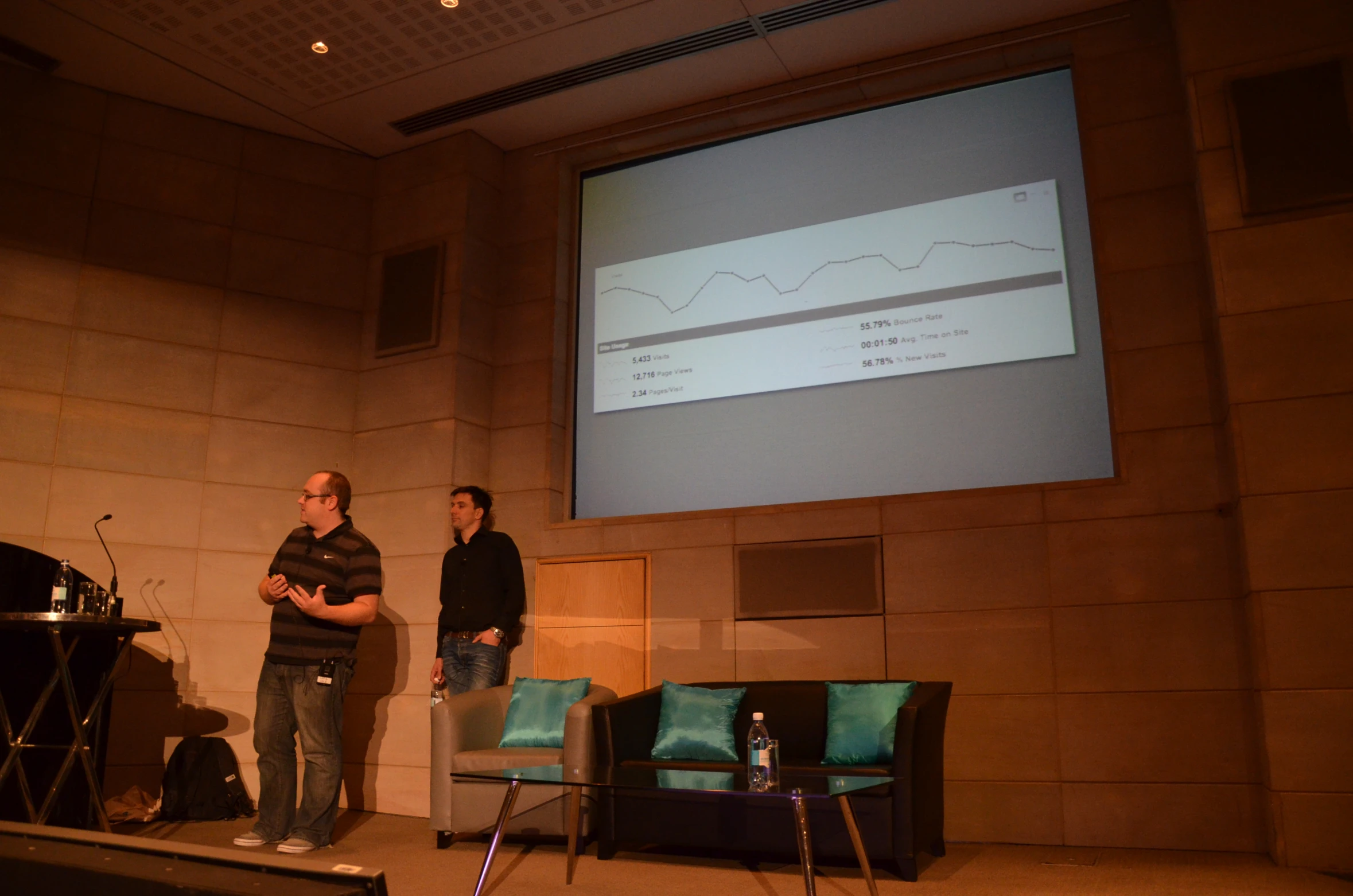 two men standing at a podium while one person speaks