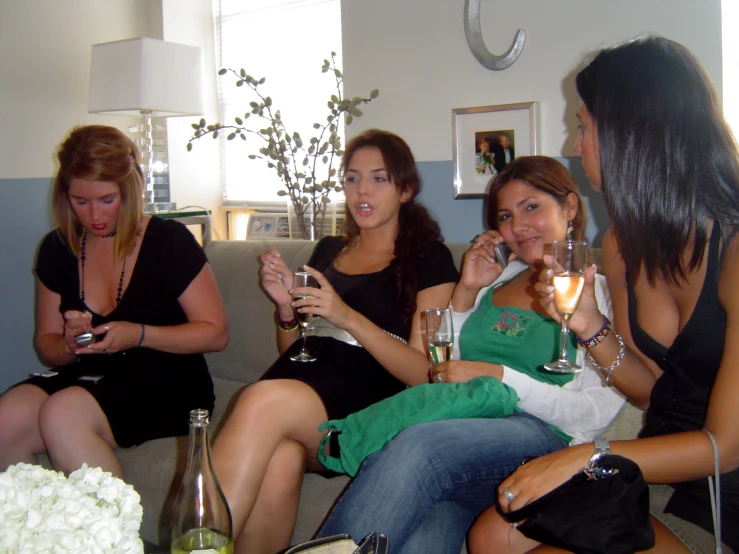 a group of women sitting on top of a couch holding wine glasses