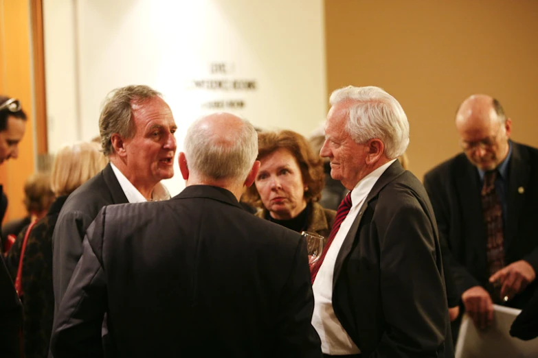two men in business suits talking with people