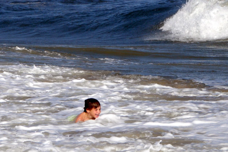 a boy swims in the ocean and looks out at the waves