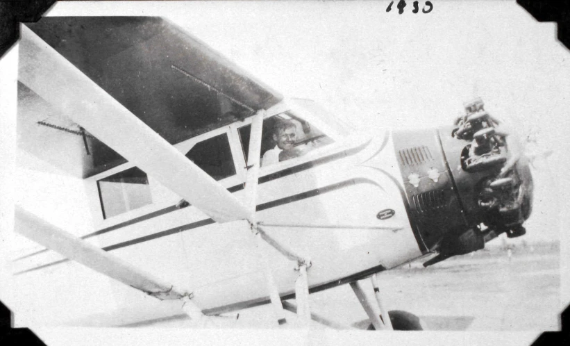 an old pograph of a young person leaning out of a plane