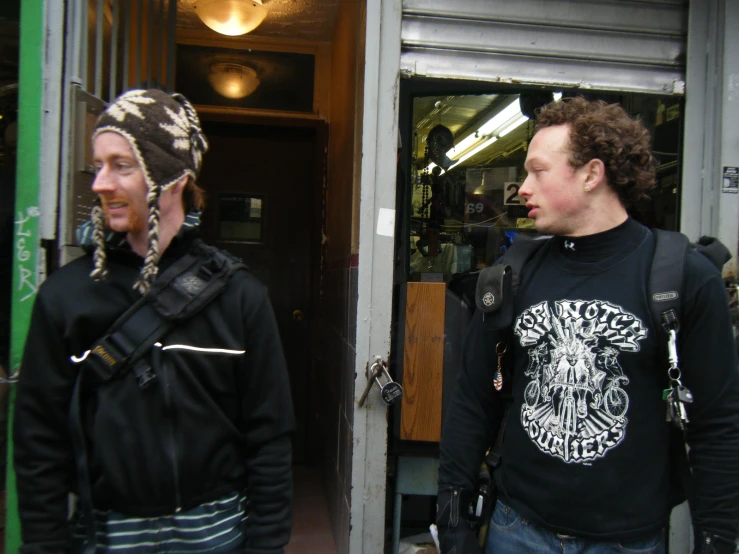 the two men are wearing winter clothes in front of the store