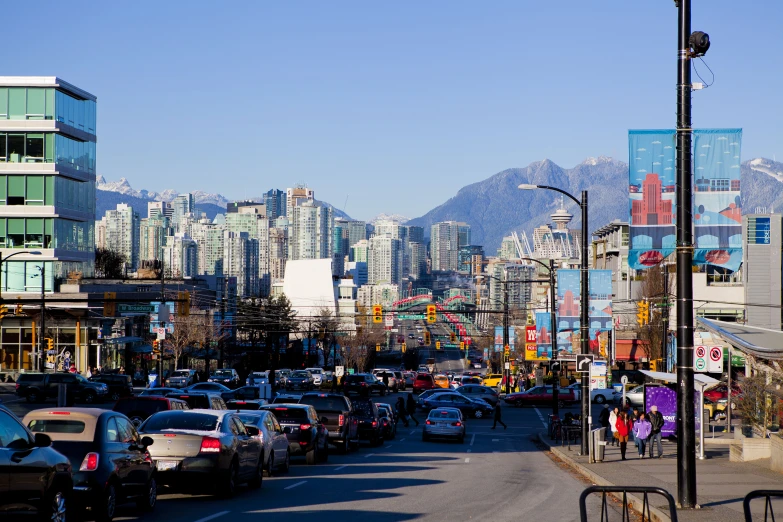 a street with buildings, cars, and pedestrians on both sides