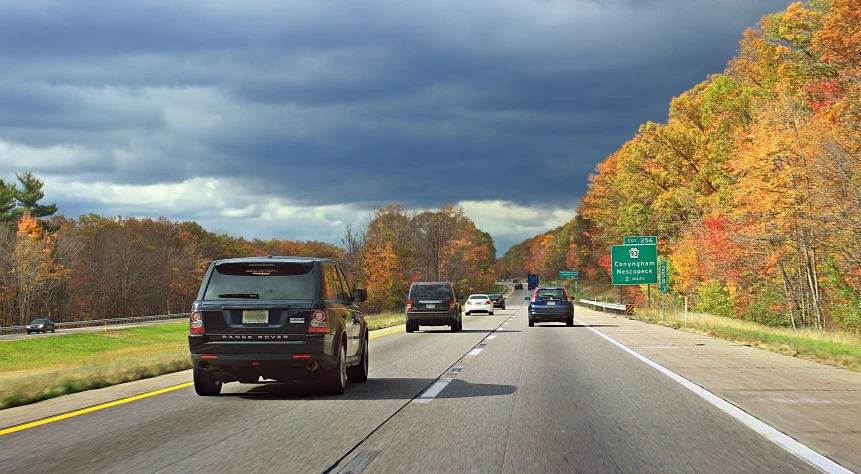 cars travel on an empty road under a stormy sky