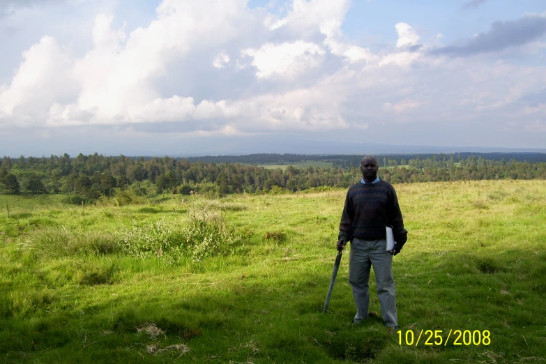 a man is standing alone in the grass on a sunny day