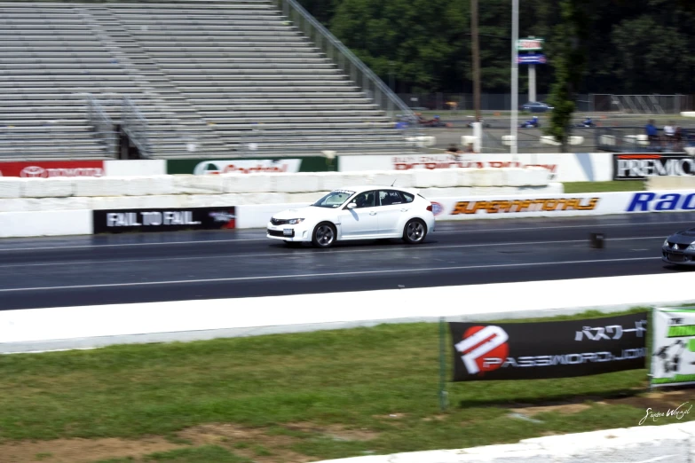 two cars racing on a race track next to empty bleachers