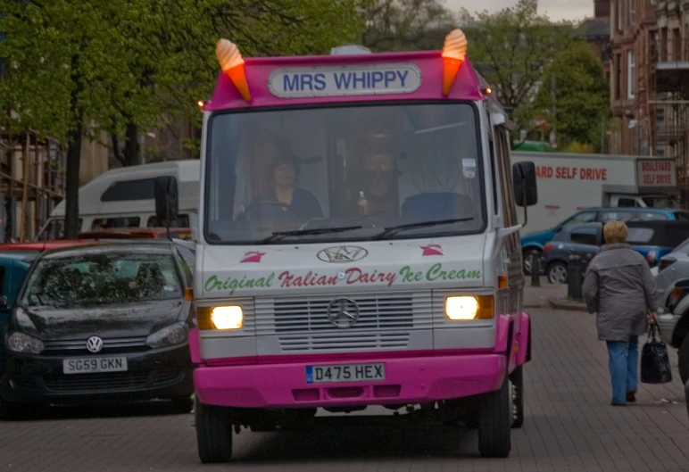 a bus driving down a street next to parked cars