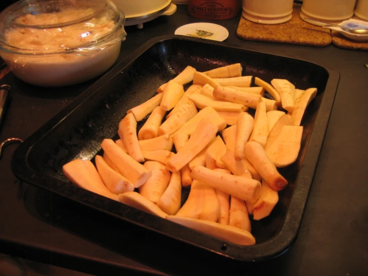 a pan of cut apples with bowls behind it