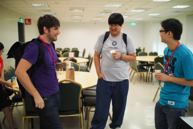 several people standing in a room with chairs around a table