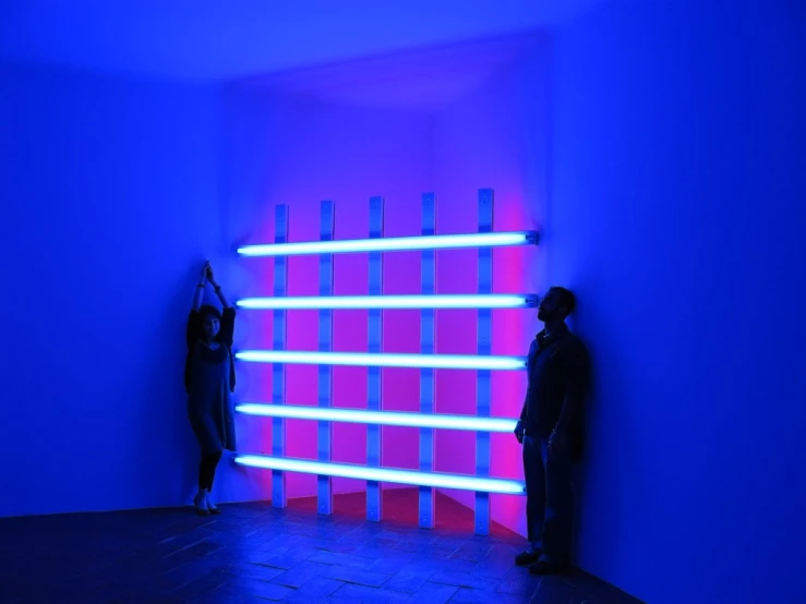 two men standing next to each other in front of a purple light