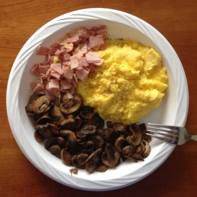 a white bowl with mushrooms, scrambled eggs and ham