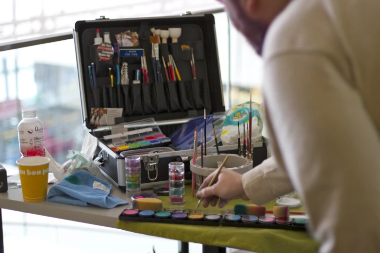 a woman painting on a table with other items nearby