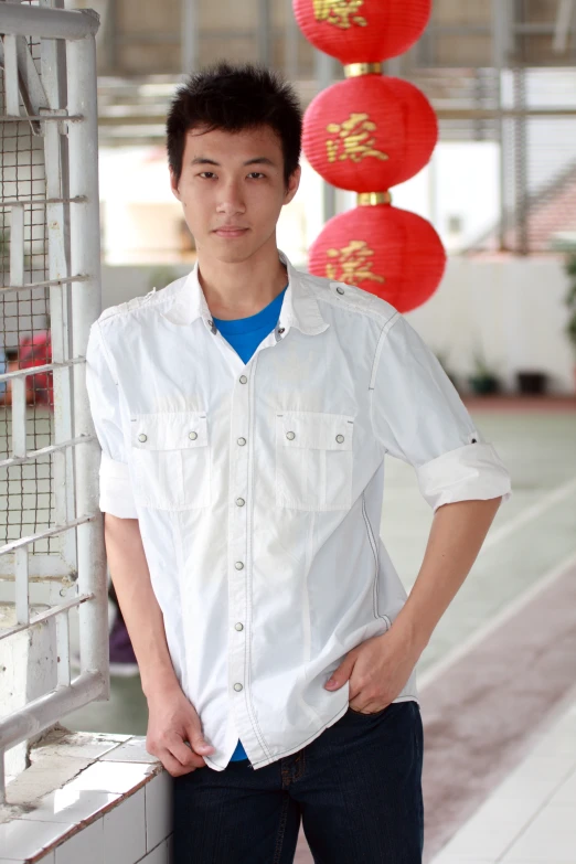 a man in white shirt posing next to a gate