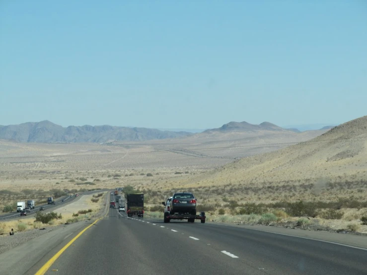 three vehicles with a trailer are travelling down a mountain road