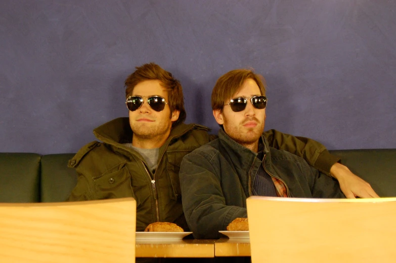 two men with sun glasses sitting on a sofa