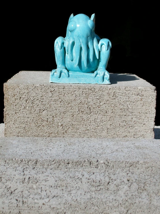 a blue elephant statue sitting on top of a cement block