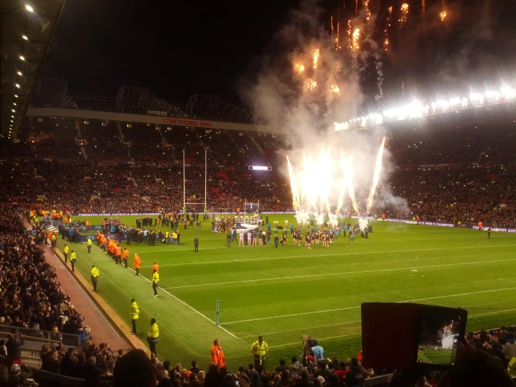 a large group of people on a field at night with fireworks