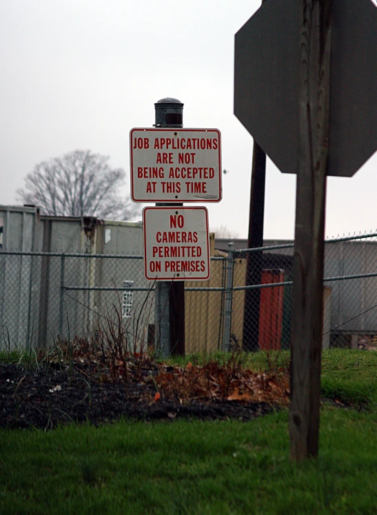 a street sign near a fence with two warning signs on it