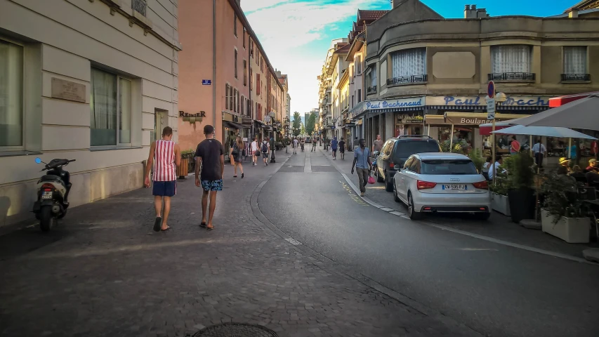 a group of people walking down a street by some buildings