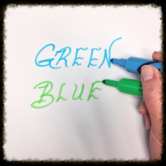 a hand writing a green blue note with marker