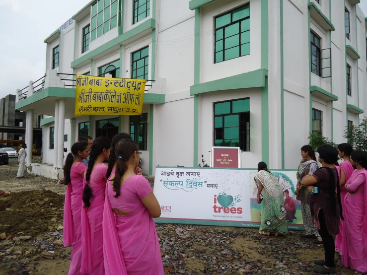 a group of women in pink are standing outside a building