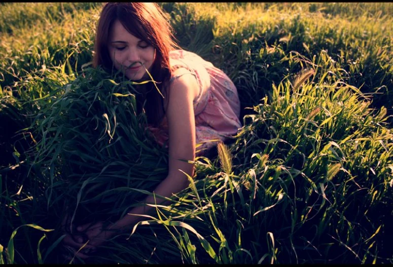 a woman laying in the grass next to some plants