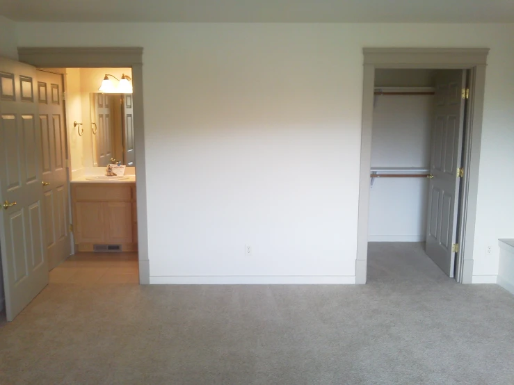 an empty living room with a door open and two doors on each side