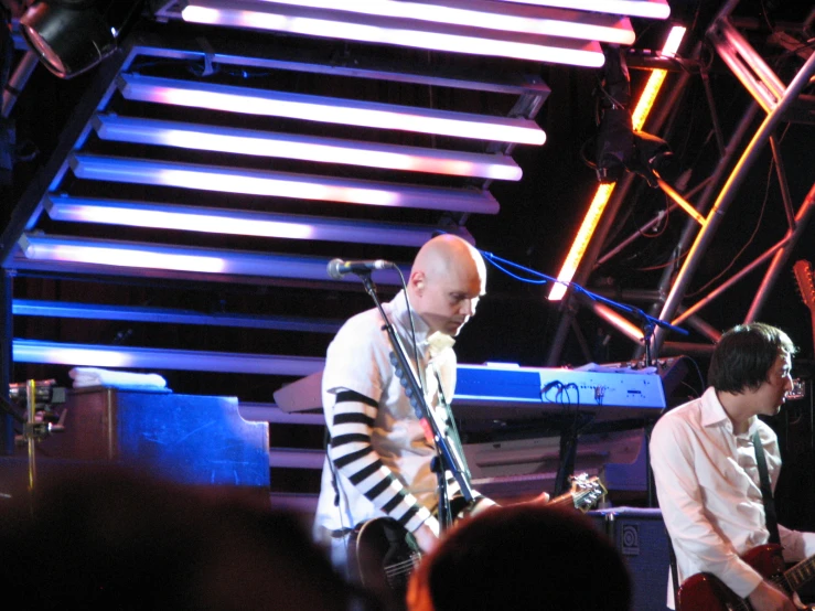 a man playing guitar in a band on stage