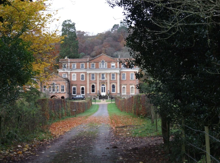 an autumn scene with a large house surrounded by trees