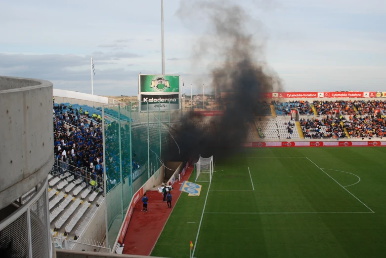 black smoke is coming out of the ground at an outdoor soccer match