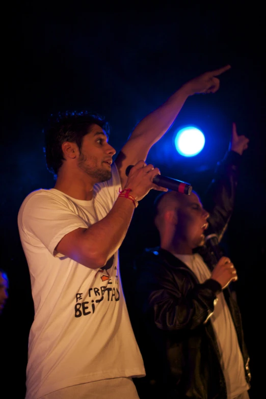 man with raised arm singing in front of audience