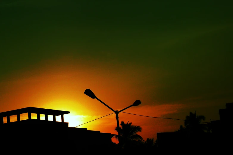 a sun rising above some silhouettes of houses