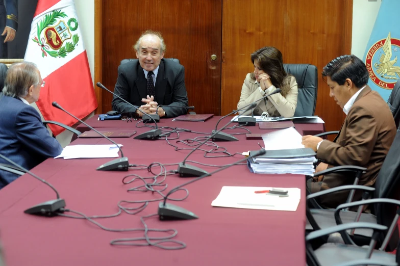 four people seated around a table in front of microphones