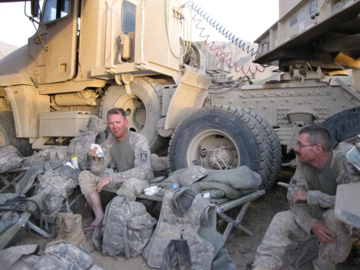 four soldiers in uniforms sitting next to the army vehicles