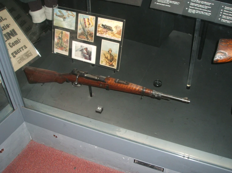 an old wooden rifle and some pictures on display