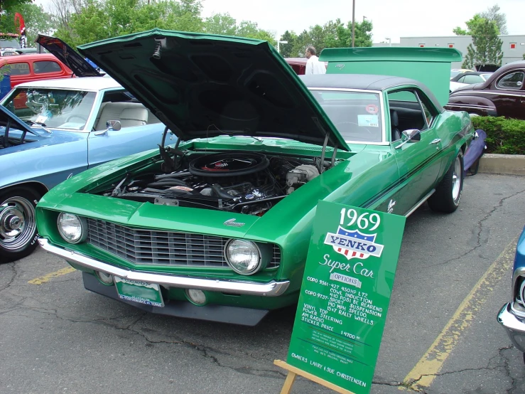 a green car with its hood open next to other cars