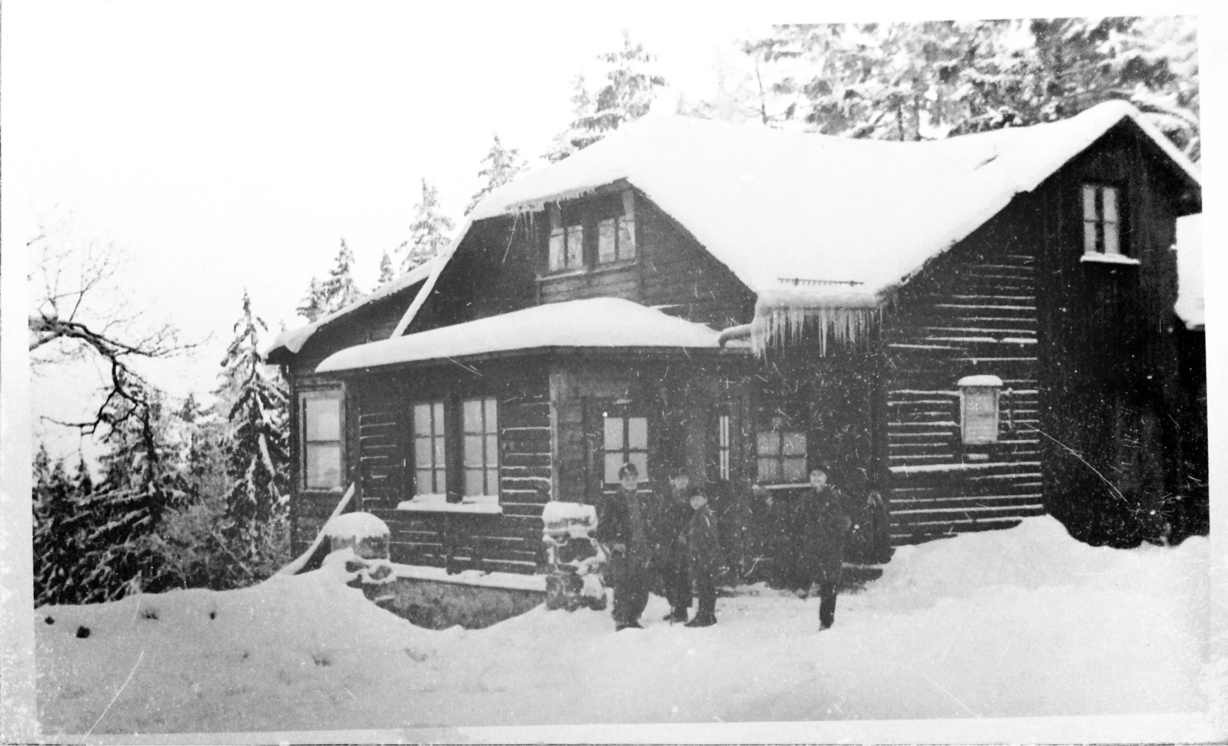 a group of men in front of a wooden cabin with snow