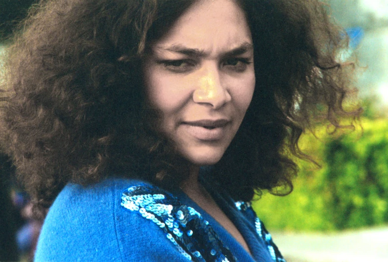 the woman with long curly hair is wearing a blue top