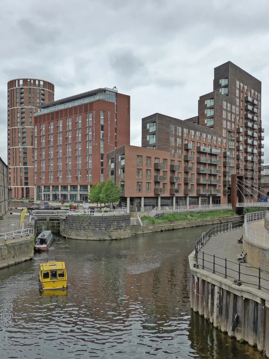 a yellow boat is on the water in front of a city building