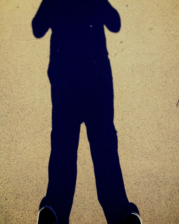 a shadow of a person standing holding a cellphone