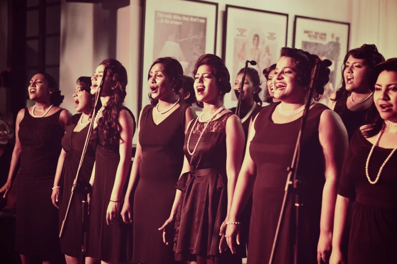 a group of women standing in a line singing into microphones