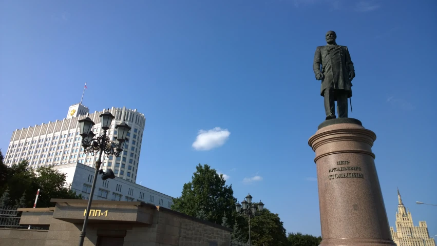 a tall statue next to a tower with two other buildings