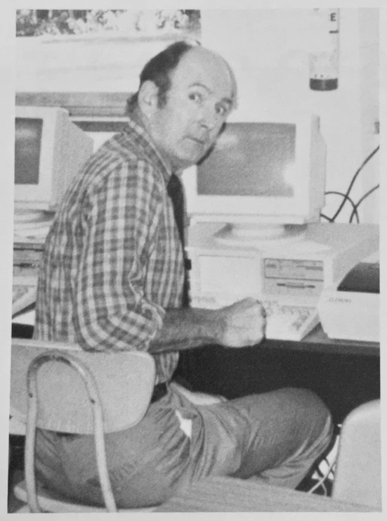 a man sitting at a desk with his book and computer