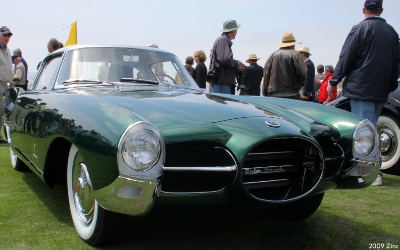 a vintage green car is parked at an event