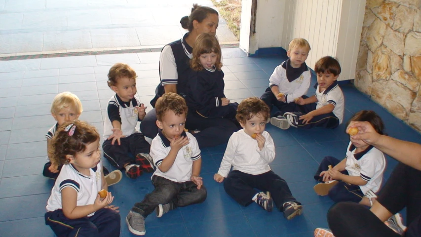 a group of children sit on the ground and eat food