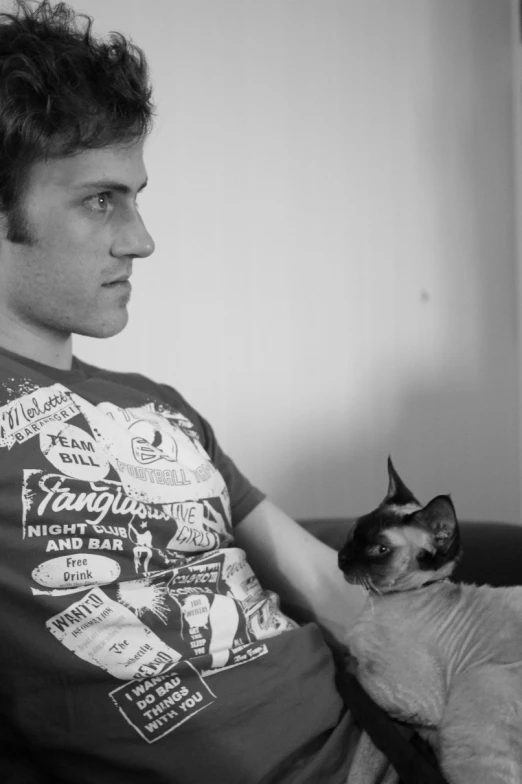 a man sitting on a couch holding a cat