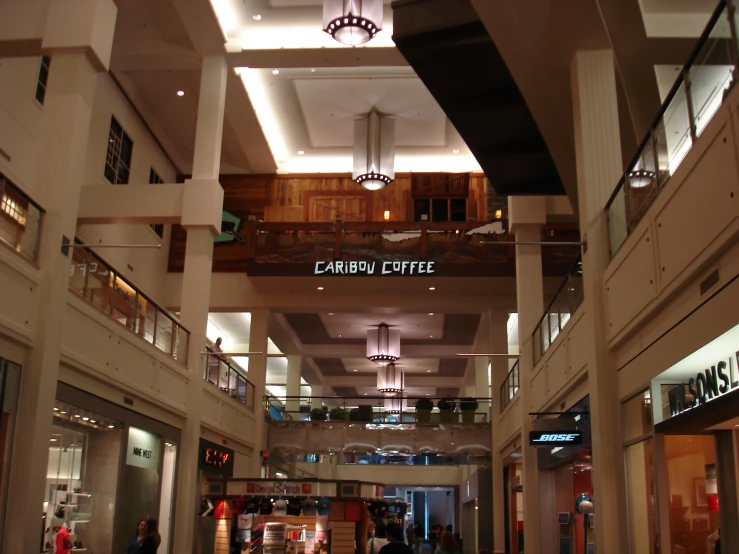 several people walking inside of a building under an open ceiling