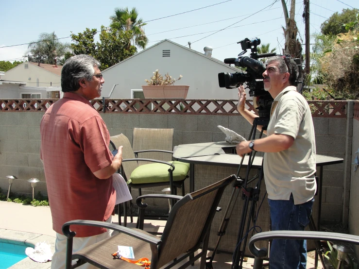 a man holding an object next to another man on a lawn chair