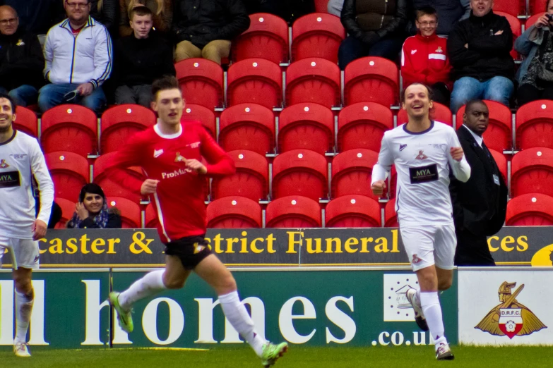 players are running in a stadium with chairs behind them