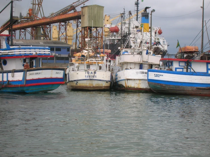 multiple fishing boats docked in the water next to a bridge